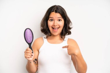 hispanic pretty girl feeling confused and puzzled, showing you are insane. hair comb concept