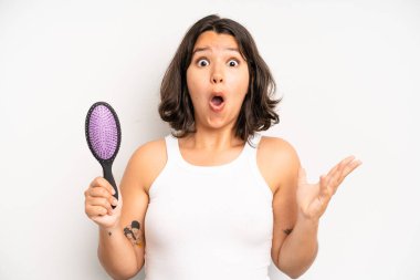 hispanic pretty girl feeling puzzled and confused, scratching head. hair comb concept