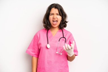 hispanic pretty girl looking shocked and surprised with mouth wide open, pointing to self. nurse concept