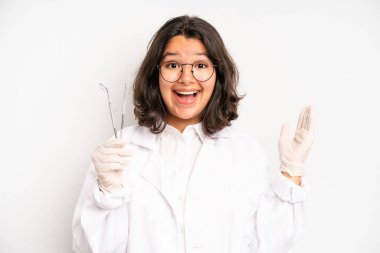 hispanic pretty girl feeling happy,giving a big shout out with hands next to mouth. dentist student concept