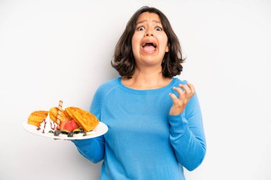 hispanic pretty girl feeling happy and facing a challenge or celebrating. waffles breakfast concept