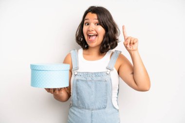 hispanic pretty girl smiling happily with a hand on hip and confident. gift box concept