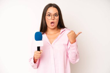 hispanic pretty woma feeling puzzled and confused and doubting. journalist with a microphone