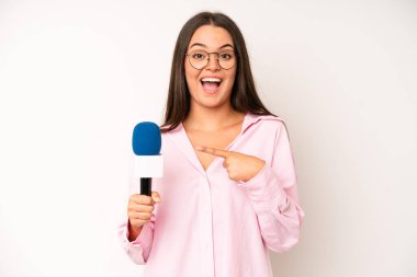 hispanic pretty woma feeling puzzled and confused, scratching head. journalist with a microphone