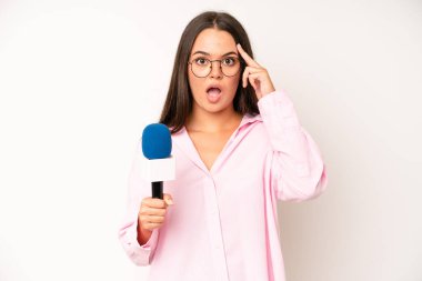 hispanic pretty woma feeling happy, showing approval with okay gesture. journalist with a microphone