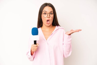 hispanic pretty woma feeling stressed, anxious or scared, with hands on head. journalist with a microphone