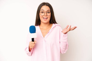 hispanic pretty woma looking happy, astonished and surprised. journalist with a microphone