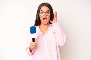 hispanic pretty woma feeling happy,giving a big shout out with hands next to mouth. journalist with a microphone