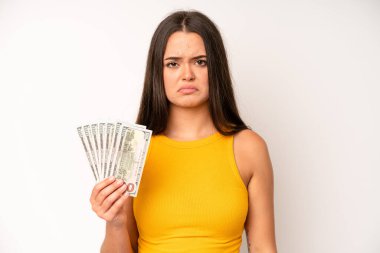 hispanic pretty woma smiling and looking happy, gesturing victory or peace. dollar banknotes concept