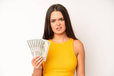 hispanic pretty woma looking shocked, scared or terrified, covering face with hand. dollar banknotes concept