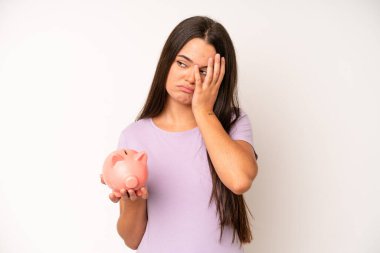 hispanic pretty woma looking very shocked or surprised. piggy bank savings concept