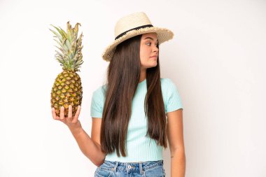 hispanic pretty woma with mouth and eyes wide open and hand on chin. pineapple and summer concept