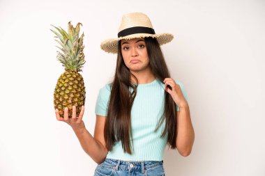 hispanic pretty woma smiling happily and daydreaming or doubting. pineapple and summer concept
