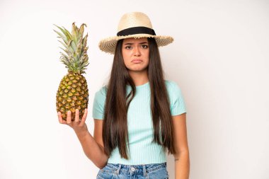 hispanic pretty woma smiling and looking happy, gesturing victory or peace. pineapple and summer concept