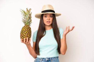 hispanic pretty woma looking happy, astonished and surprised. pineapple and summer concept