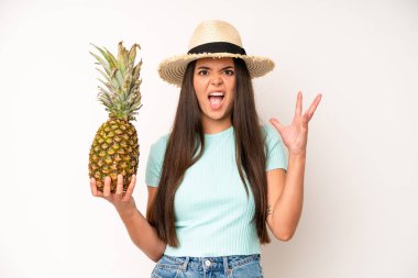 hispanic pretty woma feeling happy,giving a big shout out with hands next to mouth. pineapple and summer concept