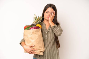 hispanic pretty woma looking very shocked or surprised. market vegetables bag concept