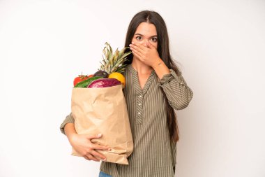 hispanic pretty woma feeling confused and puzzled, showing you are insane. market vegetables bag concept