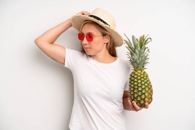 Güzel beyaz kadın mutlu bir şekilde gülümsüyor ve hayal kuruyor ya da şüphe ediyor. Yaz tatili ve ananas konsepti