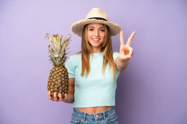 Güzel beyaz kadın gülümseyen ve mutlu görünen, zafer ya da barış işareti yapan. yaz ve ananas konsepti