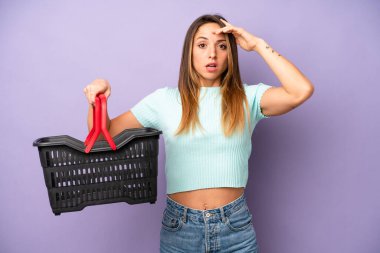 Kafkasyalı bir kadın mutlu, şaşkın ve şaşırmış görünüyor. boş alışveriş sepeti kavramı