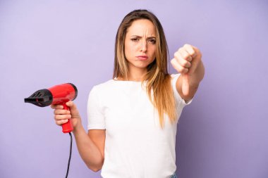 Kafkasyalı güzel bir kadın kendini kötü hissediyor, baş parmağını kaldırıyor. saç kurutma makinesi konsepti