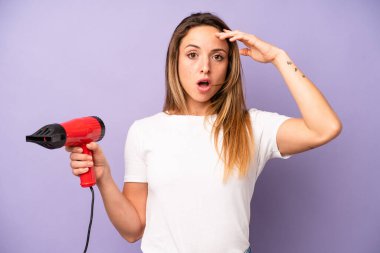 Kafkasyalı bir kadın mutlu, şaşkın ve şaşırmış görünüyor. saç kurutma makinesi konsepti