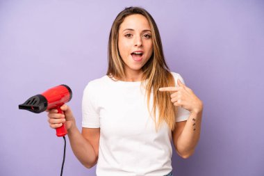 Kafkasyalı güzel bir kadın mutlu hissediyor ve heyecanla kendini işaret ediyor. saç kurutma makinesi konsepti