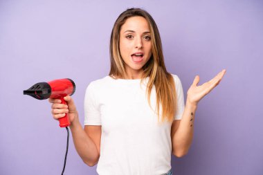 Kafkasyalı bir kadın kendini mutlu hissediyor ve inanılmaz bir şeye hayret ediyor. saç kurutma makinesi konsepti