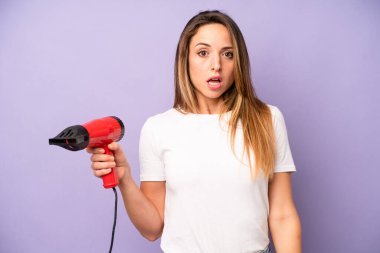 Kafkasyalı bir kadın çok şaşırmış ya da şaşkın görünüyor. saç kurutma makinesi konsepti