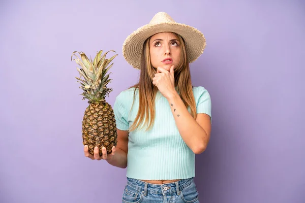 pretty caucasian woman thinking, feeling doubtful and confused. summer and pineapple concept