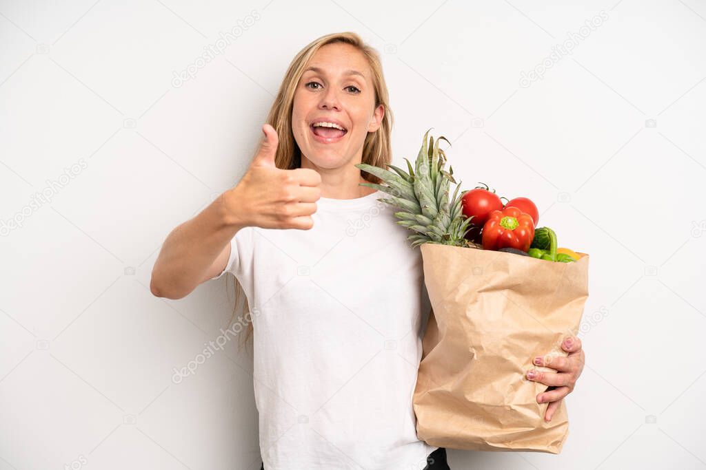 pretty caucasian woman feeling proud,smiling positively with thumbs up. chef with a market vegetables bag