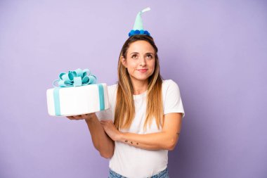 Beyaz bir kadın omuz silkiyor, kafası karışık ve kararsız. Doğum günü pastası konsepti