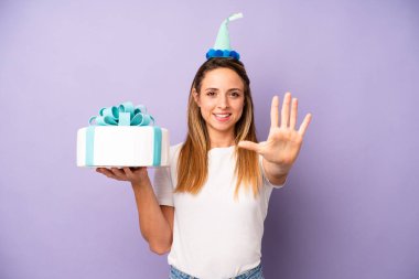Güzel beyaz kadın gülümsüyor ve arkadaş canlısı görünüyor, beş numarayı gösteriyor. Doğum günü pastası konsepti