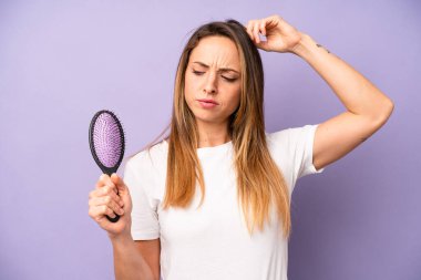 Kafası karışmış, kafası karışmış, kaşınan beyaz bir kadın. saç tarağı konsepti