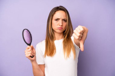 Kafkasyalı güzel bir kadın kendini kötü hissediyor, baş parmağını kaldırıyor. saç tarağı konsepti