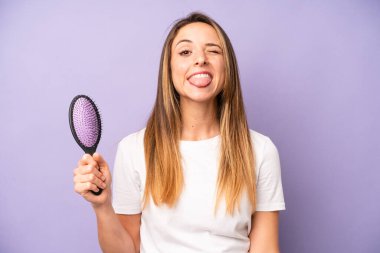 Neşeli ve asi tavırları olan, şaka yapan ve dilini dışarı çıkaran oldukça beyaz bir kadın. saç tarağı konsepti