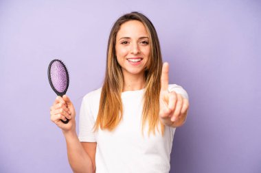 Güzel, beyaz bir kadın gururla gülümsüyor ve kendine güvenerek bir numara oluyor. saç tarağı konsepti