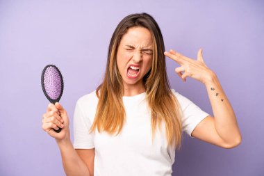 Oldukça beyaz bir kadın mutsuz ve stresli görünüyor, intihar jesti silah işareti yapıyor. saç tarağı konsepti