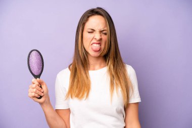 Kafkasyalı bir kadın iğreniyor, sinirleniyor ve dili dışarı çıkıyor. saç tarağı konsepti