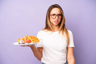 Kafası karışmış ve kafası karışmış beyaz bir kadın. Waffle ve kahvaltı konsepti