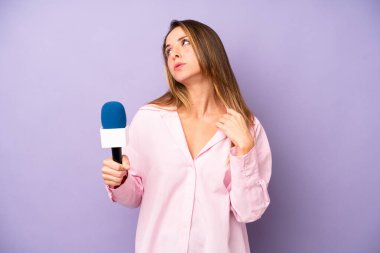 Oldukça beyaz bir kadın stresli, endişeli, yorgun ve hayal kırıklığına uğramış hissediyor. gazeteci ve mikrofon kavramı