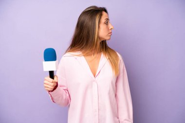 Profil görünümlü beyaz bir kadın hayal kuruyor, hayal kuruyor ya da hayal kuruyor. gazeteci ve mikrofon kavramı