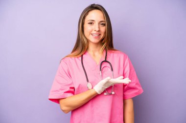 Güzel, beyaz bir kadın neşeyle gülümsüyor, mutlu hissediyor ve bir konsept gösteriyor. tıp doktoru konsepti