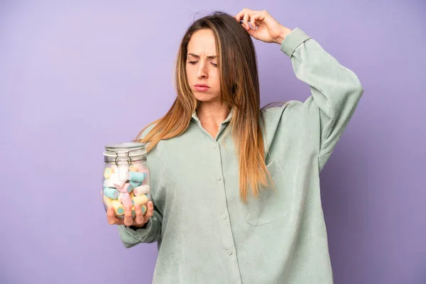 Pretty Caucasian Woman Feeling Puzzled Confused Scratching Head Candies Bottle — Stockfoto