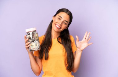 Güzel İspanyol kadın gülümsüyor ve arkadaş canlısı görünüyor, beş numarayı gösteriyor. Dolar birikimleri