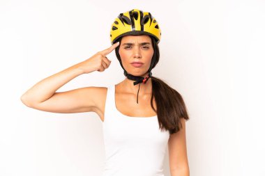 Kafası karışmış, kafası karışmış, deli olduğunu gösteren güzel İspanyol bir kadın. bisiklet kaskı konsepti