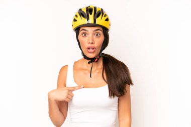 Şok olmuş ve ağzı açık, kendini işaret eden güzel İspanyol bir kadın. bisiklet kaskı konsepti