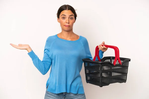 Pretty Hispanic Woman Feeling Puzzled Confused Doubting Empty Shopping Basket — Stock Photo, Image