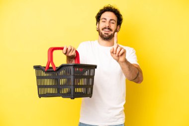 Çılgın sakallı adam gülümsüyor ve arkadaş canlısı görünüyor. Bir numarayı gösteriyor. boş pazar sepeti kavramı